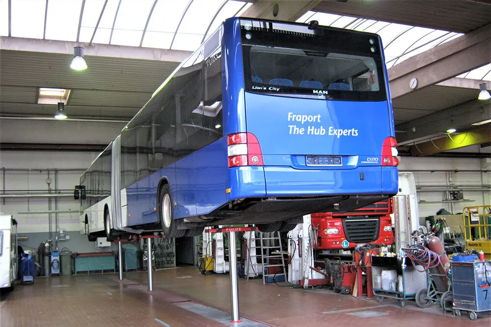 Das Bild zeigt einen Fraport-Bus auf der Hebebühne für Busse und LKWs mit mehreren Hebevorrichtungen