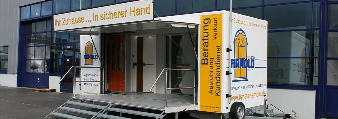 Es wird ein Anhänger geigt einer Fenster- und Türenfirma zur mobilen Präsentation ihrer Produkte z.B. auf Märkten oder Ausstellungen