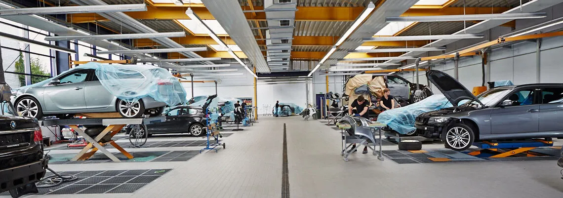 Bild zeigt die Vorbehandlungshalle, in der die Fahrzeuge stehen, bevor sie in der Lackierbox ganz oder teillackiert werden