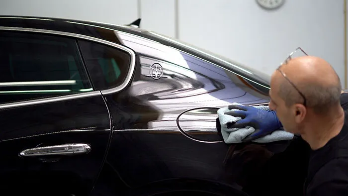 Das Bild zeigt einen Mitarbeiter beim Spot Repair. Das ist eine günstige Lösung, wenn kleine Lackschäden, etwa durch Steinschlag, ausgebessert werden.