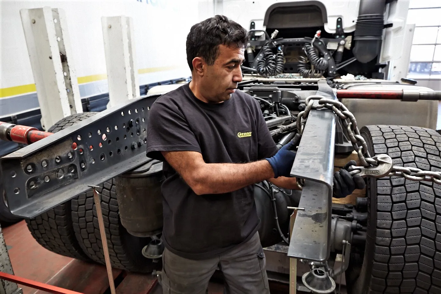 Bild zeigt einen Mitarbeiter beim richten eines LKW Aufliegergestells mit schwerer Kette.