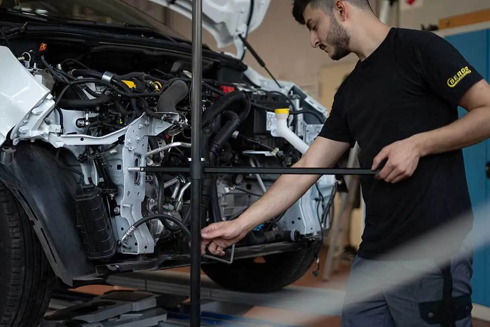Bild zeigt einen Mitarbeiter, der an einem Fahrzeug mit abgebauter Frontschürze arbeitet