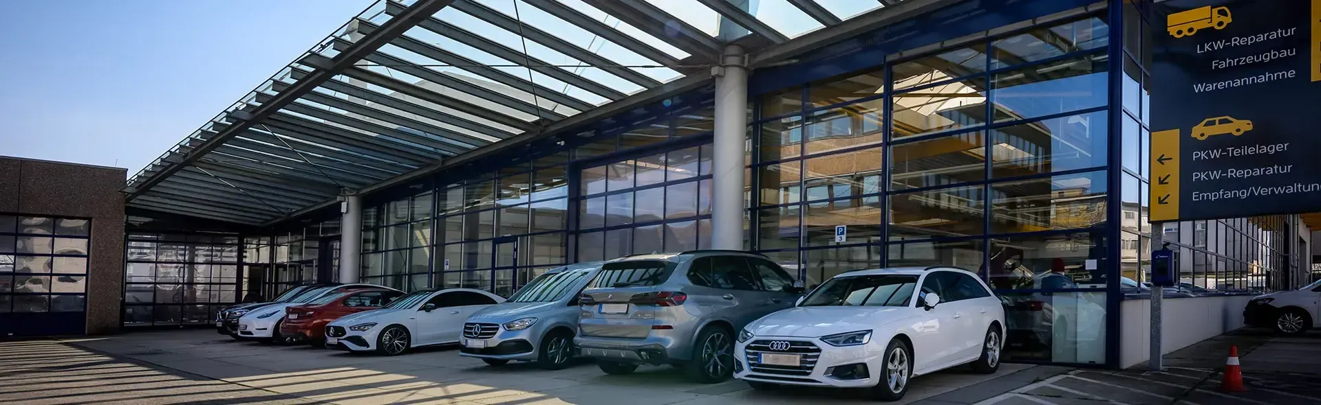 Auf dem Bild ist die große, moderne Reparaturhalle zu sehen, mit vielen Fahrzeugen vor der Front